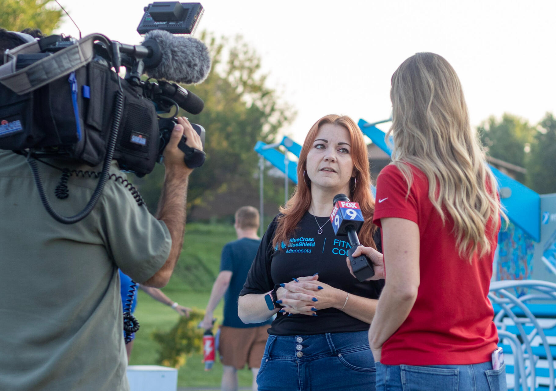 Two women being filmed for a TV show on an outdoor fitness court