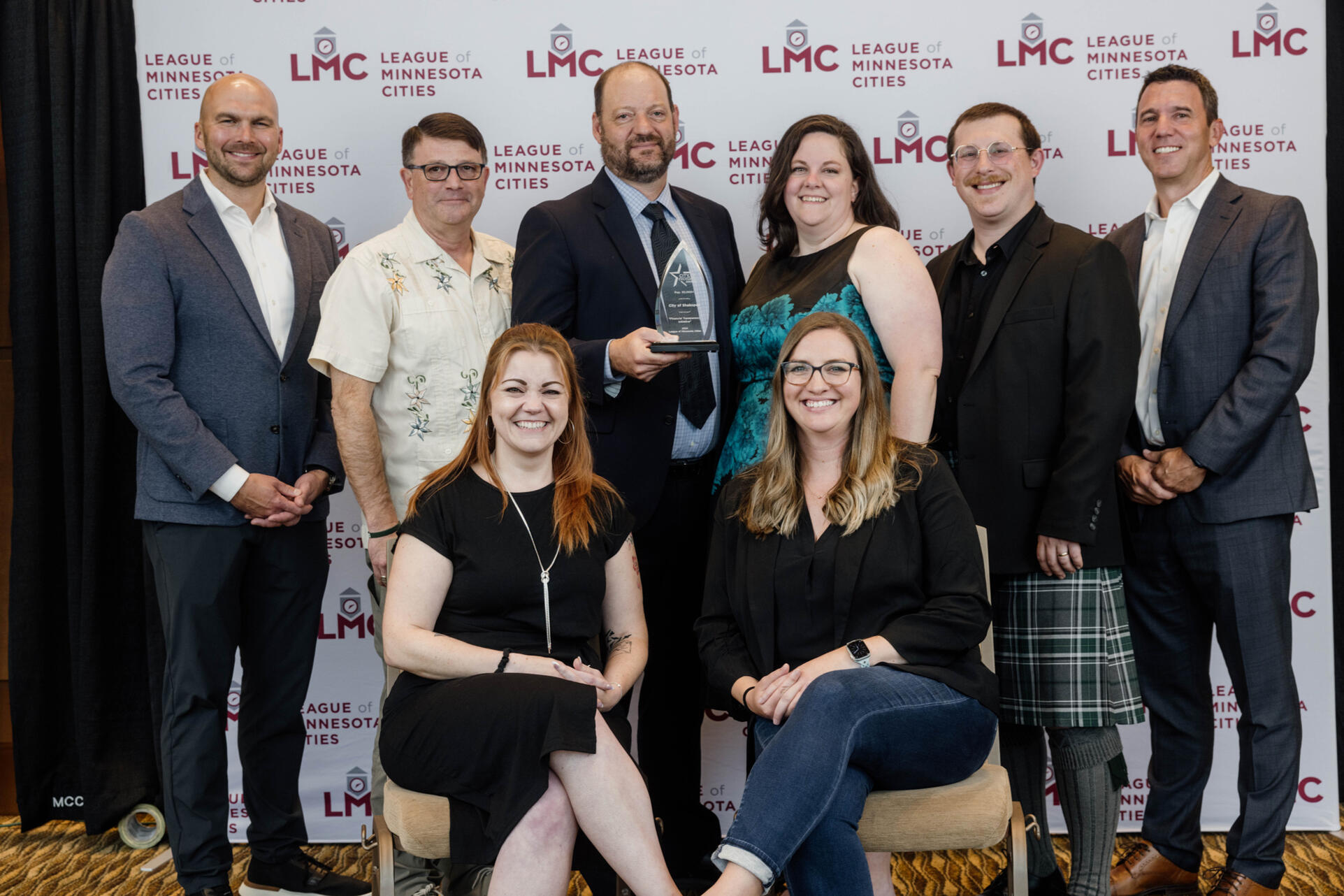 A group of eight people take a professional photo to celebrate winning an award.